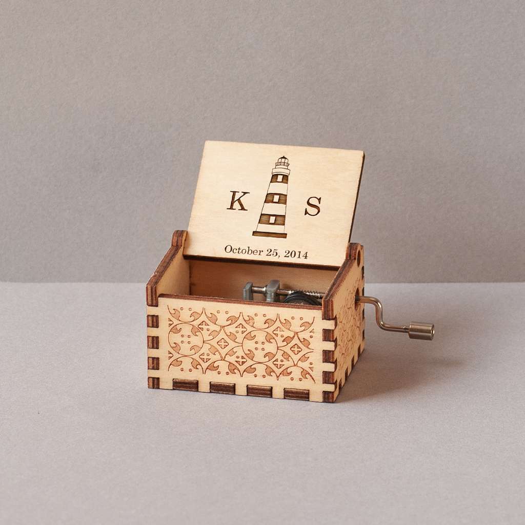 Caja musical de madera grabada con un faro, iniciales y fecha