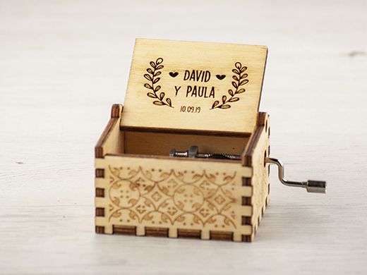 Caja musical de madera grabada con una corona de laurel, nombres y fecha
