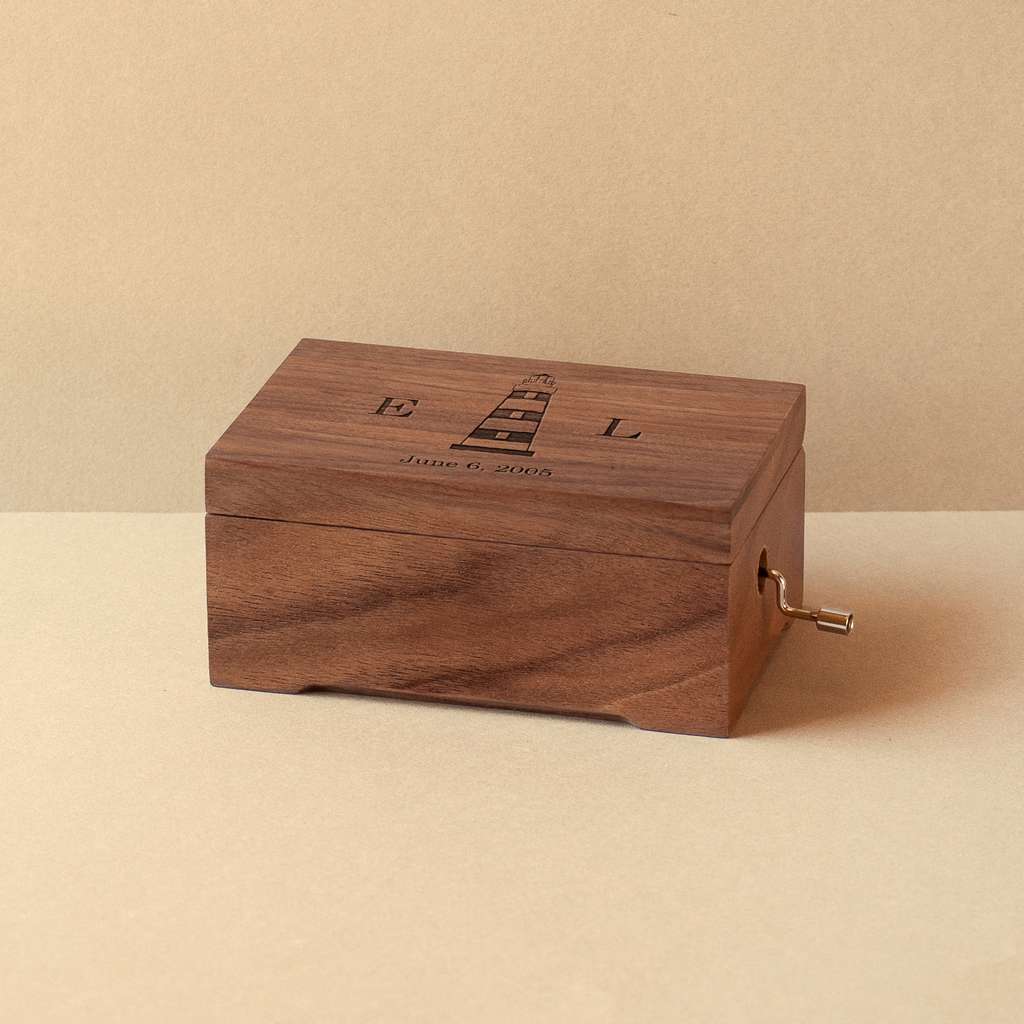 Caja musical mediana de madera de nogal con un faro, iniciales y fecha